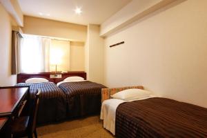 大阪市にあるホテルサンライフのベッド2台とデスクが備わるホテルルームです。