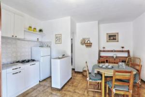 una cucina con tavolo e una cucina con elettrodomestici bianchi di Villa Artistica trilo 3 a Capoliveri