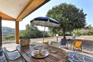 a wooden table with an umbrella on a patio at Villa Artistica trilo 3 in Capoliveri