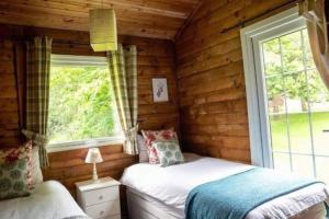 um quarto com 2 camas num chalé de madeira em Grouse Lodge em Dunoon
