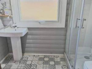 a white bathroom with a sink and a shower at Grouse Lodge in Dunoon