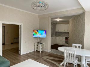 a living room with a white table and a tv at Ecohouse in Bishkek