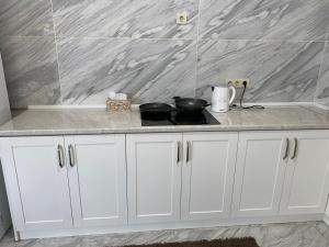 a kitchen counter with white cabinets and a stove at Ecohouse in Bishkek