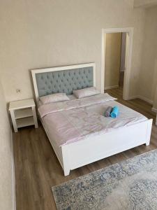 a bedroom with a large white bed with a headboard at Ecohouse in Bishkek
