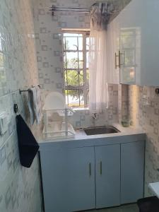 cocina blanca con fregadero y ventana en Stellar 1-bedroom apartment in Madaraka Estate, Nairobi, en Nairobi