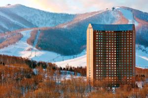 The Westin Rusutsu Resort في روسوتسو: مبنى أمام جبل مع منحدر التزلج