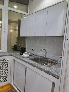 una cocina con armarios blancos y fregadero en Апартамент в центре города Худжанд en Khujand