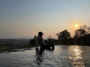 Eine Frau, die bei Sonnenuntergang im Wasser sitzt in der Unterkunft Chale Pepe in Carrancas