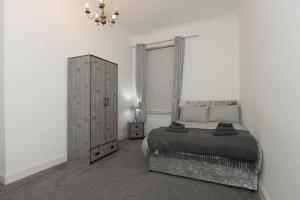 a bedroom with a bed and a cabinet and a chandelier at Maze Beach Getaway in Ayr