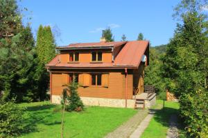 une maison en bois avec un toit rouge dans un champ dans l'établissement Chata U Jozefa, à Malý Lipník