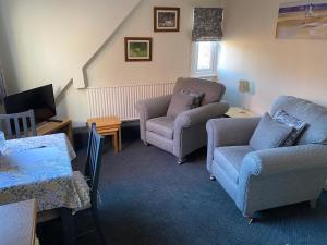 a living room with two chairs and a couch and a tv at Buile Hill Holiday Flats in Llandudno