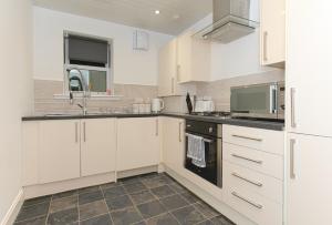a kitchen with white cabinets and black appliances at Maze Beach Getaway in Ayr