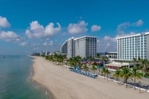 a beach with buildings and palm trees and the ocean at The Westin Fort Lauderdale Beach Resort in Fort Lauderdale