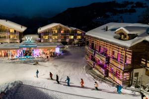 a group of people on skis in the snow in front of buildings at W Verbier in Verbier
