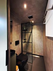 a bathroom with a black toilet in a room at Diamond Suite in the woods in Holten