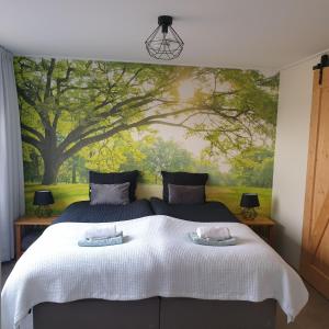 a bedroom with a large bed with a tree mural at Vakantiewoning "In Between" in Oostkapelle