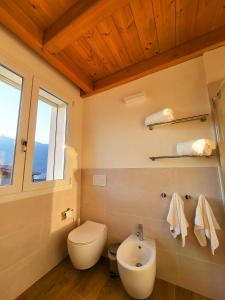 baño con aseo y lavabo y ventana en Sol Lakeview, en Sale Marasino