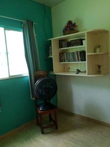a room with a fan and a chair and a book shelf at Sítio Família Morais in Salvaterra