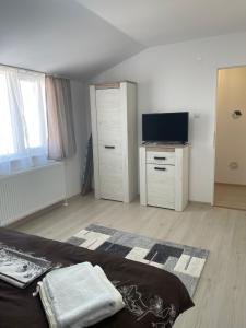 a bedroom with a bed and a dresser and a television at Jokai Apartments Nr7, code entry in Sfântu-Gheorghe