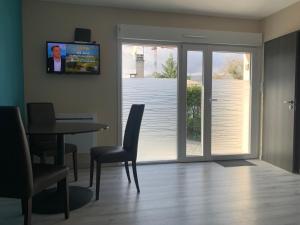a living room with a sliding glass door with a table and chairs at LE BRON ACCUEIL - TOPDESTINATION-LYON in Bron