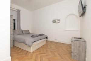 een slaapkamer met een bed en een houten vloer bij Maze Dream Apartment in Ayr