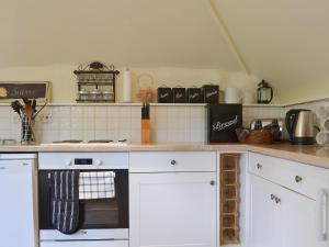 a kitchen with white cabinets and a stove top oven at The Stable in Camerton