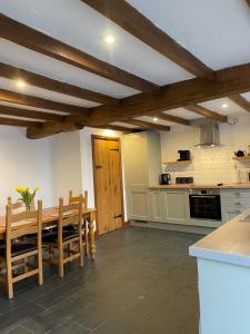 cocina con mesa de madera y sillas en una habitación en Cilhendre Holiday Cottages - The Old Cowshed, en Swansea