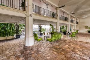un vestíbulo con sillas verdes, mesas y plantas en Historic Palm Beach Hotel #1106 en Palm Beach