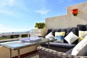 a patio with a couch and a table on a balcony at Seaviews Balcones de Chaparral 3 Bed Apt in Mijas Costa