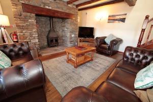 a living room with leather furniture and a fireplace at Cilhendre Holiday Cottages - The Old Cowshed in Swansea
