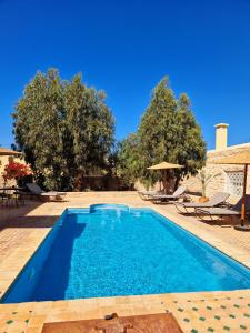 a swimming pool in a yard with chairs and trees at Villa nouran in Ghazoua