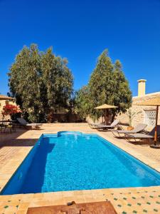 a swimming pool in a yard with chairs and trees at Villa Nouran - Chambre Hôte in Ghazoua