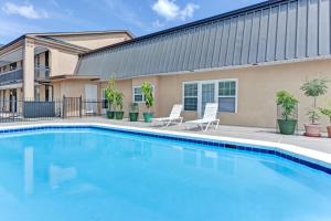 a swimming pool with two chairs and a building at Super Inn & Suites Carrollton in Carrollton