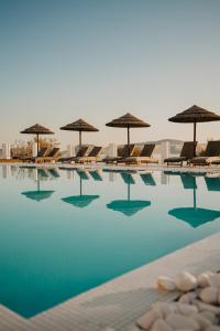 a swimming pool with chairs and umbrellas at Paros Bay in Parasporos