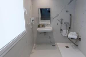 a white bathroom with a sink and a mirror at Hotel Agaró in Chipiona