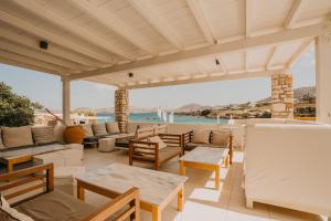 a patio with tables and chairs and a view of the ocean at Paros Bay in Parasporos