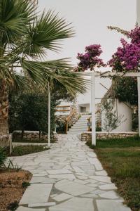 a stone walkway with palm trees and a building at Paros Bay in Parasporos