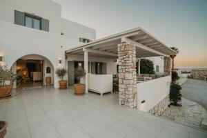 a white house with a patio with a stone pillar at Paros Bay in Parasporos