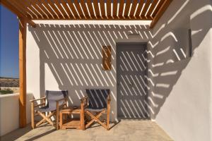 two chairs sitting on a porch with a wooden pergola at Paros Bay in Parasporos