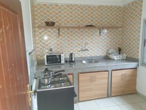 a small kitchen with a stove and a microwave at Lovely 1-Bed duplex house in Abidjan