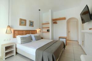 a bedroom with a large white bed and a flat screen tv at Paros Bay in Parasporos