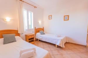 een kamer met twee bedden en een raam bij Villa Llebeig 155TS Son Bou By MENORCARENTALS in Son Bou +21 foto's