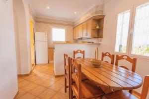 een keuken en eetkamer met een houten tafel en stoelen bij Villa Llebeig 155TS Son Bou By MENORCARENTALS in Son Bou