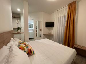 ein Schlafzimmer mit einem großen weißen Bett und einem TV in der Unterkunft Ca' Maggiolo in Cinto Caomaggiore