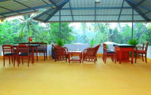 a dining room with tables and chairs and a large window at Alapatt Homestay in Alleppey