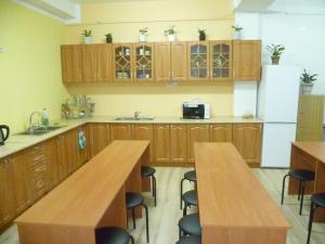 a kitchen with wooden cabinets and wooden tables and a refrigerator at Hostel Vitan in Lviv