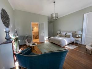 a bedroom with a bed and a blue chair at Maison M on the Dordogne in Sainte-Foy-la-Grande