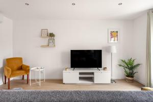 a white living room with a tv and a chair at Lisbon Vibes - Monsanto house in Lisbon
