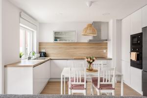 una cocina con armarios blancos y una mesa con sillas. en Lisbon Vibes - Monsanto house, en Lisboa