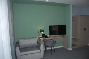 a room with a chair and a desk with a television at Hotel w Dobieszkowie in Stryków